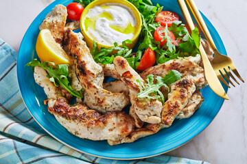 Grilled chicken with arugula salad on a blue plate