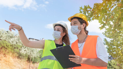 Portrait of worker and engineer wearing face masks checking production process and discussing...