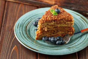 Piece of honey cake with nuts on green plate