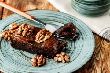 Piece of chocolate cake with nuts on green plate