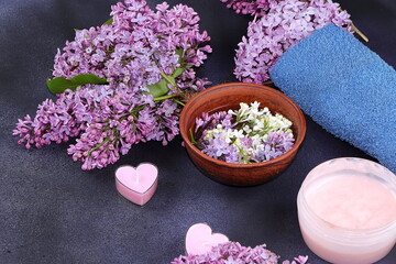 Spa and wellness composition with fragrant water from lilac flowers in a wooden bowl on a dark background, aromatherapy and skin and body care, flat lay, top view, lifestyle concept and modern woman