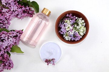 Spa and wellness composition with lilac flowers aromatic water in wooden bowl on gray background, aromatherapy and skin and body care, flat lay, lifestyle concept, selective focus