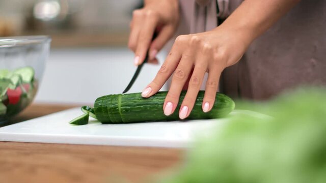 Closeup beautiful female hands cutting fresh organic cucumber. Shot on RED Raven 4k Cinema Camera