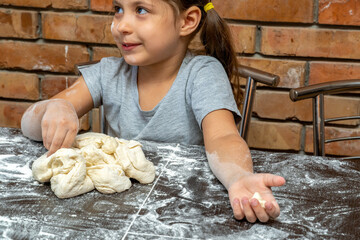 cute little girl kneading dough, preparing dough for baking