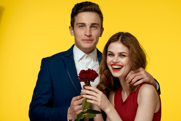 lovers man and woman with a red rose in their hands hugging on a yellow background romance relationship love family