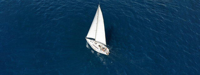 Aerial drone ultra wide photo of sailboat cruising deep blue sea