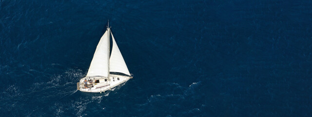 Aerial drone ultra wide photo of sailboat cruising deep blue sea