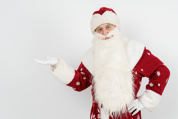 Santa Claus shows a pointing gesture, raising the palm of his hand to the top. Isolated background.