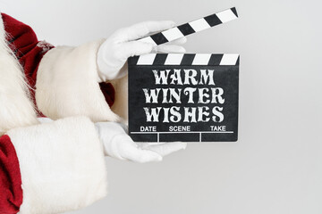 Santa Claus is holding a cracker in his hands - a numerator with the text - WARM WINTER WISHES