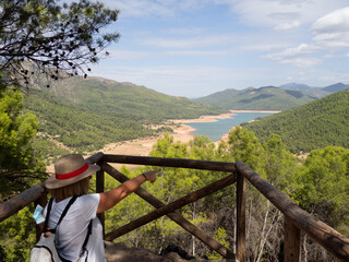 Woman with hat looking towards the Pantano del Tranco at the Bujaraiza Castle Observatory in the Cazorla Natural Park