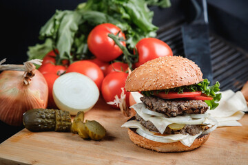 Tasty grilled burger with with beef, cheese, vegetables.  Delicious grilled Cheeseburger on a dark background. 