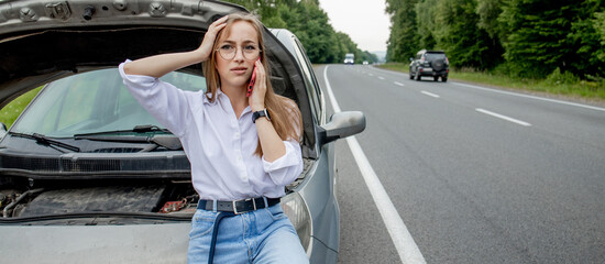 Young woman opening bonnet of broken down car having trouble with her vehicle. Worried woman talking on the phone near broken car. Girl model standing near the broken car calling for auto service - Powered by Adobe