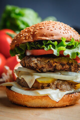 Tasty grilled burger with with beef, cheese, vegetables.  Delicious grilled Cheeseburger on a dark background. 