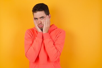 Handsome man with sweatshirt over isolated yellow background Tired hands covering face, depression and sadness, upset and irritated for problem