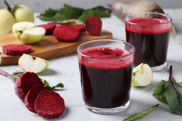 Two glass of fresh juice with beetroot and apples. Chopped beet and apples on gray table. Close up. Horizontal format