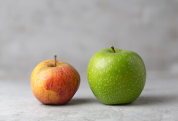 Two green and red apples on a gray concrete background