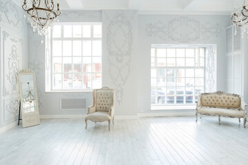 Luxury rich living room interior design with elegant classic furniture and wall decorations. Large light white room with big window