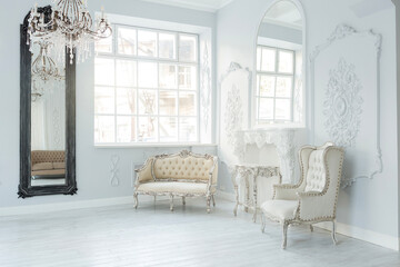 Luxury rich living room interior design with elegant classic furniture and wall decorations. Large light white room with big window