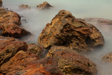 Rocks on the beach bathed by marine foam.