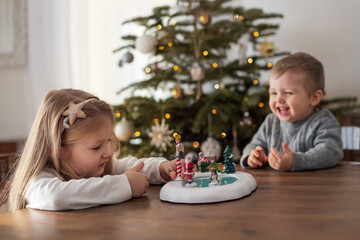 Sister and brother play with ceramic figurines for Christmas