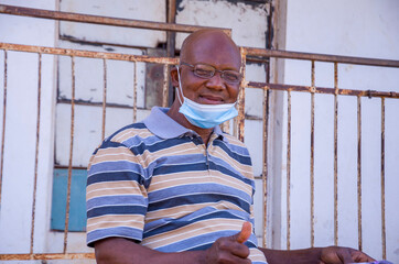 aged handsome african man wearing face mask preventing himself from the outbreak in society and reading a book