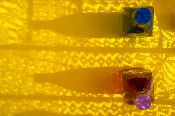 Blue and purple bottles with shadows on yellow background.