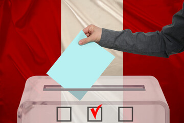 male voter drops a ballot in a transparent ballot box against the background of the national flag...