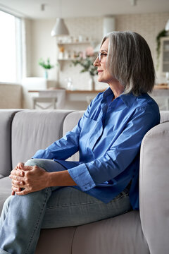 Classy Relaxed Mature Old Woman Relaxing Sitting On Couch At Home. Peaceful Middle Aged Grey-haired Lady Resting On Sofa In Modern Living Room Enjoying Lounge, No Stress, Peace Of Mind, Looking Away.