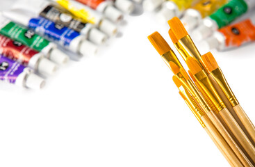 New brushes of different sizes on a wood base and acrylic paints, artist's palette, on a white background..Copy space