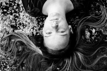 Girl lying on the ground with her long hair, top view. Black and white photo.