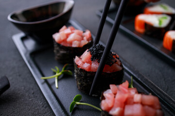 Eating sushi. Chopsticks taking gunkan maki sushi from plate. Japanese food, deluxe restaurant menu, delicious traditional seafood