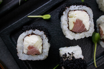 Japanese cuisine, food background. Tasty appetizing sushi rolls with tuna and caviar served on black plate, copy space
