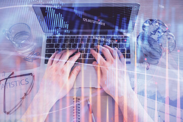 Multi exposure of man's hands typing over computer keyboard and forex graph hologram drawing. Top view. Financial markets concept.