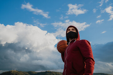 A young man with a face mask holding a basketball.