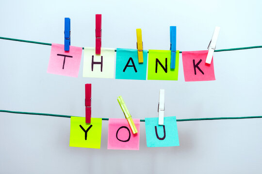 COLOR STICKY NOTES WITH LETTERS ON THE CLOTHES LINE SPELLING THANK YOU. WHITE BACKGROUND.