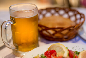 Cold draft lager beer in a glass mug,next to some salad and bread in basket,Podgorica,Montenegro.