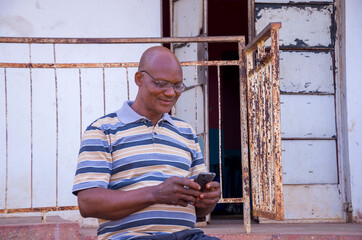 handsome elderly african man wearing strip clothes feeling excited about what he saw on his phone.