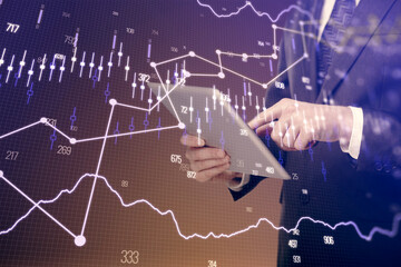 Double exposure of man's hands holding and using a digital device and forex graph drawing. Financial market concept.