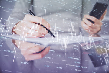 Double exposure of forex chart sketch hologram and woman holding and using a mobile device. Financial market concept.