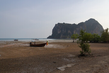 Fototapeta na wymiar Railay East beach at low tide, in the background of the mountain, on the beach boat stranded