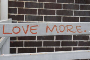 Obraz premium The Words Love More written in market on white fence brick background
