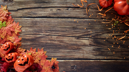 Halloween pumpkins with autumn fall leaves over wooden