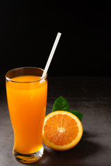 Orange juice with slice on black background.