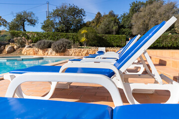 Obraz premium blue cushion deckchair on the edge of a swimming pool in summer