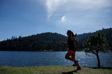 Obraz premium Atleta corriendo al aire libre cerca de un lago con montañas al fondo