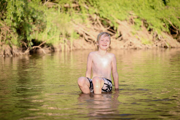 Boy swimming in fresh water river at dusk in New South Wales, Australia
