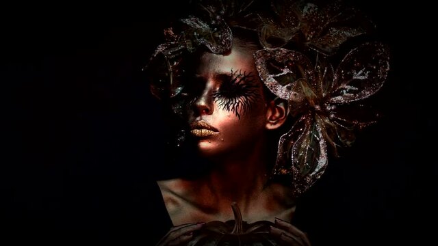 Creative art project. Golden young woman. Halloween female model, face in gold. Halloween fashion makeup. Slow motion.