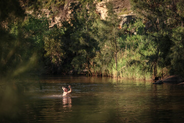 Fototapeta na wymiar Boy swimming in river in beautiful afternoon light