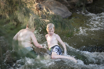Boys playing in rushing water in the Goulburn River near Mudgee, New South Wales
