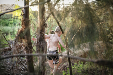 Young boy playing among trees on riverside